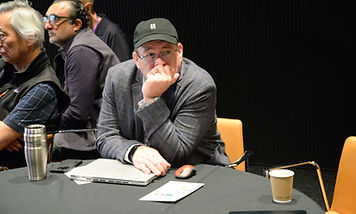 An attendee seated at a table with a laptop, resting their chin on one hand