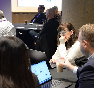 Attendees seated around a table with laptops and coffee