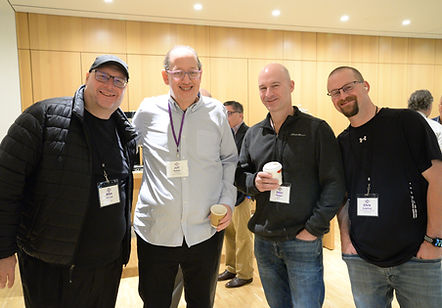 Four attendees with name badges posing together