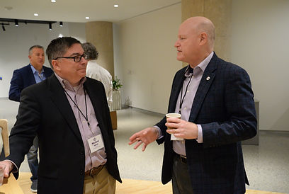 Two attendees talking in a hallway, one holding a coffee cup
