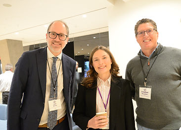 Three attendees with name badges posing together