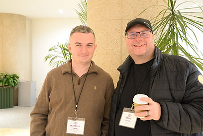 Two attendees posing together, one holding a coffee cup